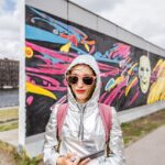 Portrait of a young woman tourist standing in front of the Berlin wall in Germany