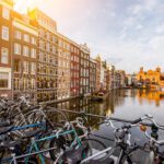 Morning view on the beautiful buildings and bicycles on the Damrak avenue in Amsterdam